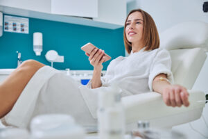 beautiful elegant female sitting in armchair and getting intravenous vitamin drip treatment in beauty center